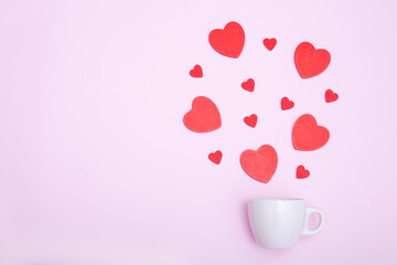 Coffee cup and red wooden hearts on a pink background. The concept of Valentine's day, love, dating and wedding. Symbol of a romantic gift or marriage proposal. Copy space, minimalism.