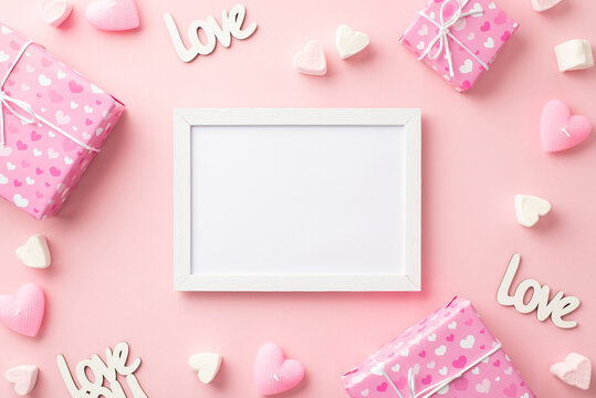 Valentine's Day concept. Top view photo of photo frame gift boxes heart shaped marshmallow inscriptions love and candles on isolated pastel pink background with blank space