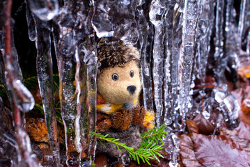 A hedgehog made of wool and mohair using the dry felting technique hugs beech cones in an icicle cave in the forest