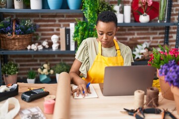 African american woman florist using laptop at florist