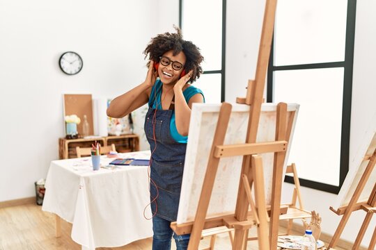 Young african american woman listening to music looking draw at art studio