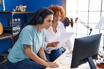 Two women musicians composing song using computer at music studio