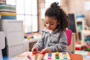 African american toddler playing with maths puzzle game standing at kindergarten