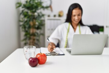 Young latin woman wearing nutritionist uniform working at clinic