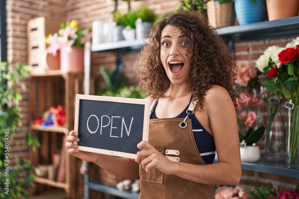 Sticker hispanic woman with curly hair working at florist holding open sign celebrating crazy and amazed for