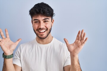 Hispanic man with beard standing over white background celebrating mad and crazy for success with...