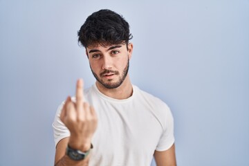 Hispanic man with beard standing over white background showing middle finger, impolite and rude fuck off expression