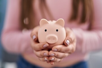 Young woman holding piggy bank at home