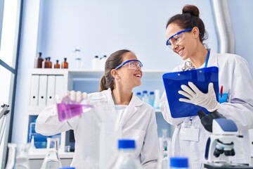 Woman and girl wearing scientist uniform working at laboratory