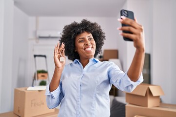 Fototapeta na wymiar African american woman having video call holding key at new home