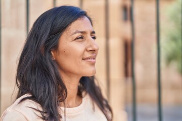 Young beautiful hispanic woman smiling confident looking to the side at street