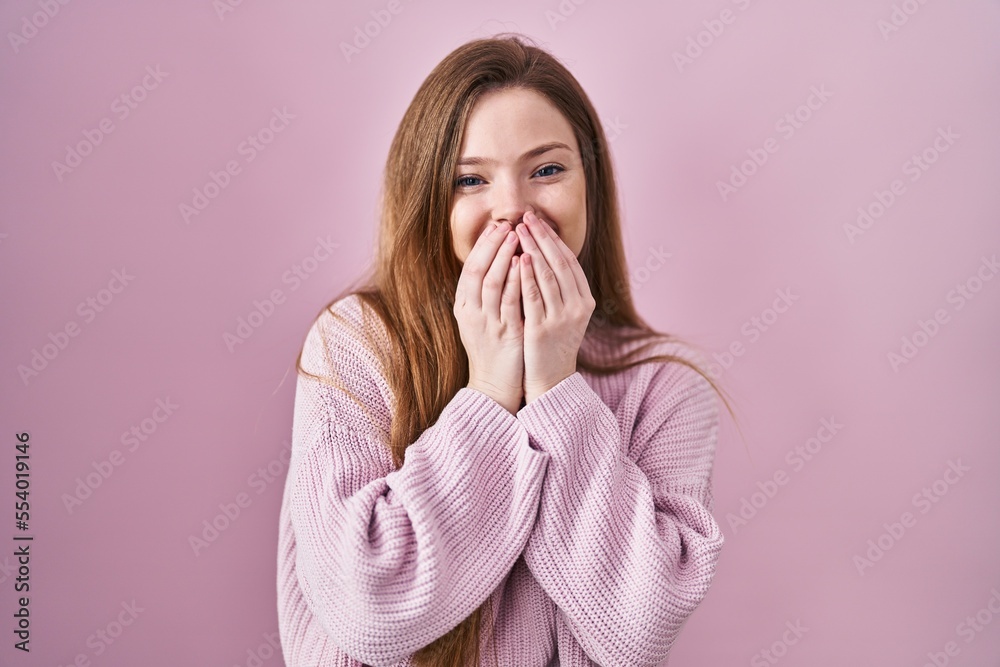 Poster Young caucasian woman standing over pink background laughing and embarrassed giggle covering mouth with hands, gossip and scandal concept