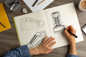 The designer draws sketches of shoes on paper.