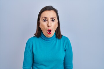 Middle age hispanic woman standing over isolated background afraid and shocked with surprise expression, fear and excited face.