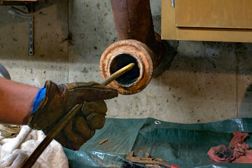 Hands of a plumber as he runs a camera scope and cleaning machine through the main pipe to unclog...