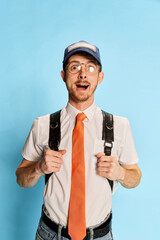 Portrait of young man, student in casual clothes posing isolated over blue background. Good mood. Success