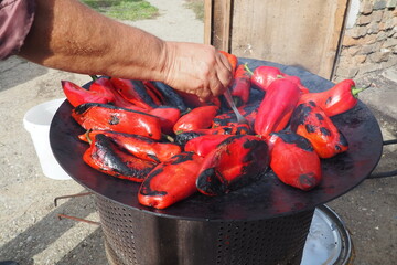 Roasting red peppers for a smoky flavor and quick peeling. Thermal processing of the pepper crop on a metal circle. Brazier container used to burn charcoal fuel for cooking, heating or cultural