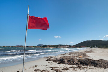 Red flag at beautiful white sandy beach at San Teodoro Sardinia.