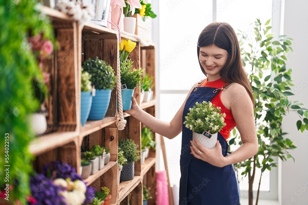 Sticker Young caucasian woman florist holding plant at florist