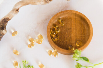 top view of omega 3 oil or collagen capsules on wooden dish on table