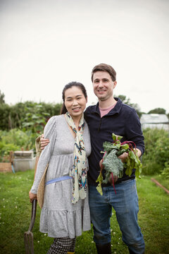 Portrait happy couple with harvested beets in garden