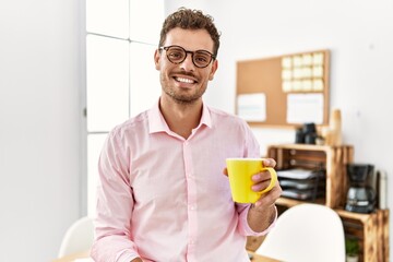 Young hispanic man smiling confident drinking coffee at office
