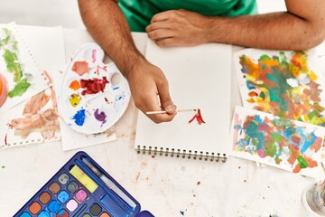 Young hispanic man drawing on notebook at art studio