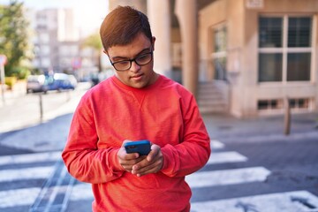 Down syndrome man using smartphone with serious expression at street
