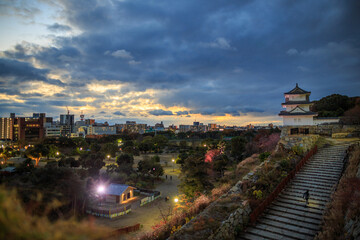 Dramatic sunset breaks through clouds over historic Japanese Castle park