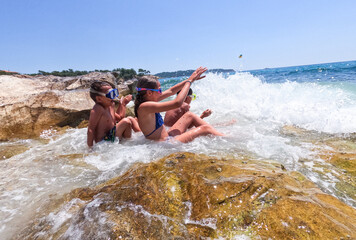 Children have fun on the beach with crashing and splashing sea waves. Summer childhood great time.	