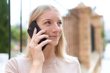 Young blonde woman smiling confident talking on the smartphone at street