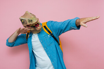 Man with backpack and lizard mask on pink background.