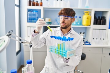Young arab man scientist measuring liquid holding test tubes at laboratory