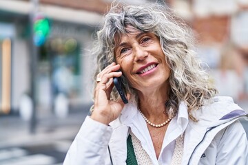 Middle age woman smiling confident talking on the smartphone at street