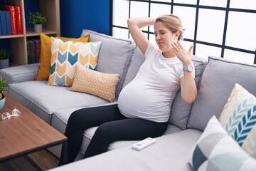 Young pregnant woman touching belly suffering heat weather at home