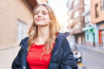 Naklejka na ściany i meble Young blonde woman smiling confident looking to the side at street