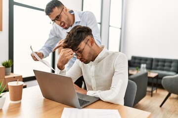 Two hispanic men business workers arguing at office