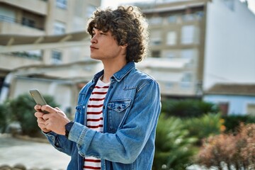 Young hispanic man using smartphone at the city