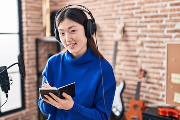 Chinese woman artist smiling confident composing song at music studio