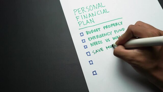 Man's hand writing personal financial plan list. Personal finance planning written by hand. Budgeting, funding, saving, investing. Making list of personal money goals avoid crisis and recession.