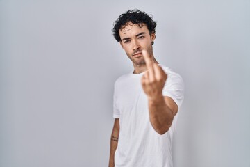Hispanic man standing over isolated background showing middle finger, impolite and rude fuck off expression