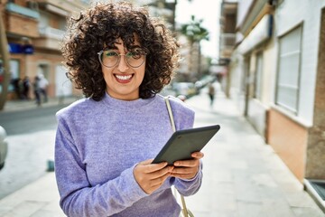 Young middle east woman smiling confident using touchpad at street