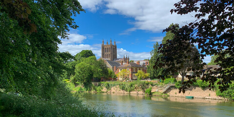 Fototapeta na wymiar Looking across the River Wye to Hereford Cathedral on a beautiful spring day in Hereford, Herefordshire, UK. A mobile phone photo with some phone or tablet post processing.