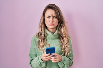 Fototapeta premium Young caucasian woman using smartphone typing message skeptic and nervous, frowning upset because of problem. negative person.
