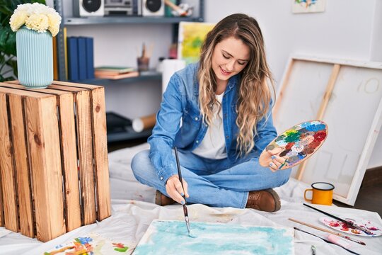 Young woman artist drawing sitting on floor at art studio