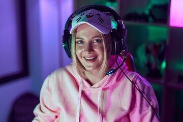 Young blonde woman streamer smiling confident wearing headphones at gaming room