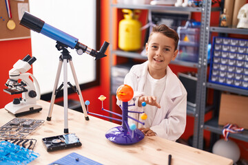 Adorable hispanic toddler student smiling confident using telescope at classroom