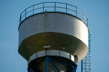 New modern water tower on the background of blue sky and forest. Methods of water storage for irrigation of agricultural crops in difficult climatic and weather conditions. A barrel with water