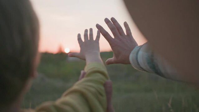 Families. Closeup father and son watching beautiful sunset, touching sky with hands and holding them together. Relationship.