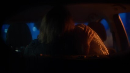 Mid 20s Caucasian couple passionately kissing on a backseat of a car